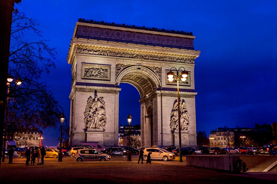 The Arc de Triomphe in Paris, France at twilight in front of a very deep blue sky.